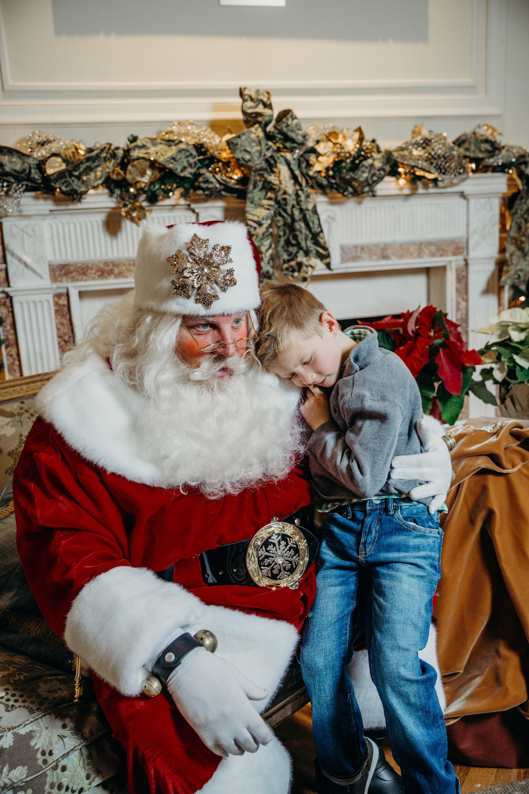 Santa Doug by a fireplace with a young boy leaning on his knee